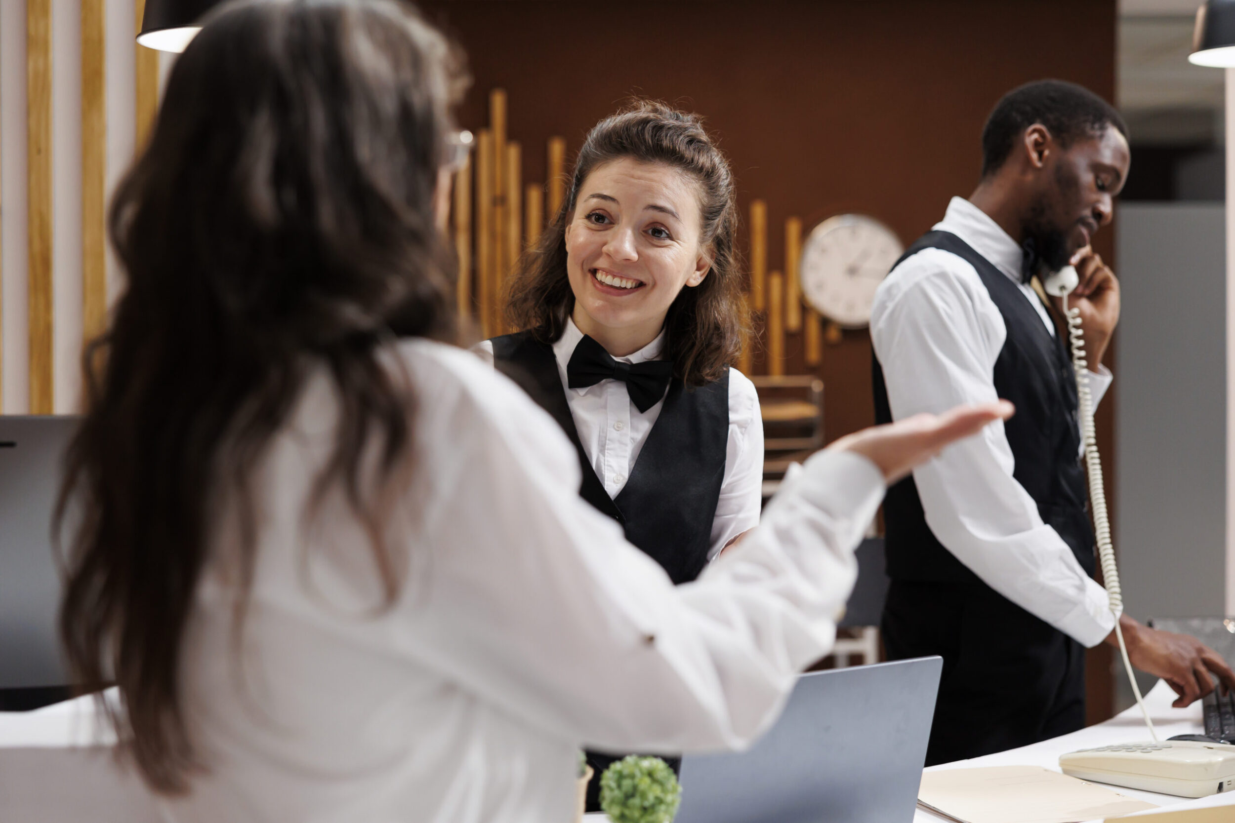Hotel staff member smiling warmly while speaking with a guest.
